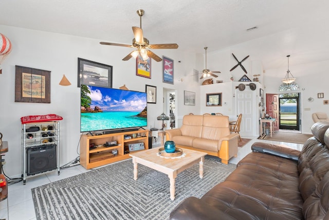 living room with a textured ceiling, ceiling fan, light tile patterned floors, and vaulted ceiling