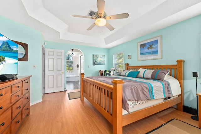 12354 Golden Eagle St, Port Saint Lucie, FL 34987 - bedroom featuring arched walkways, a raised ceiling, light wood finished floors, and a ceiling fan
