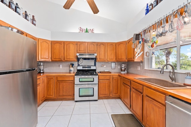 kitchen with light tile patterned floors, stainless steel appliances, high vaulted ceiling, and sink