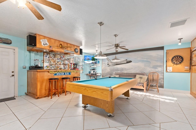 recreation room featuring ceiling fan, a textured ceiling, bar, light tile patterned floors, and pool table