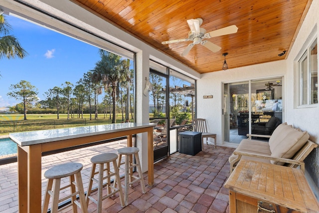 sunroom / solarium featuring ceiling fan, a water view, and wood ceiling