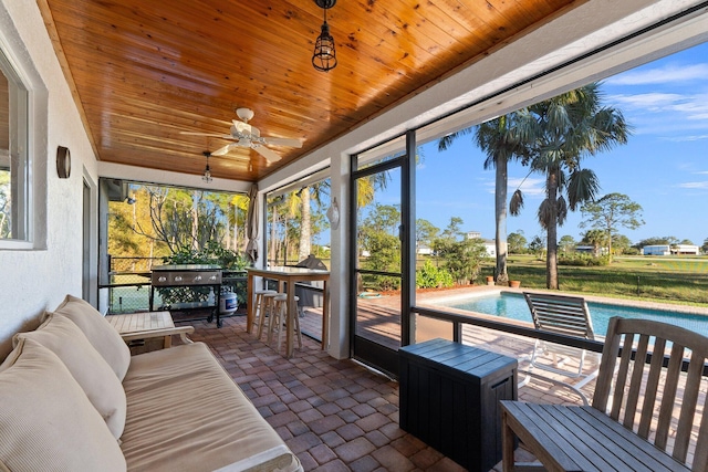 sunroom with ceiling fan and wood ceiling