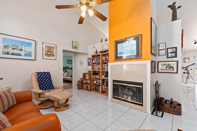 tiled living room with ceiling fan, a fireplace, and high vaulted ceiling