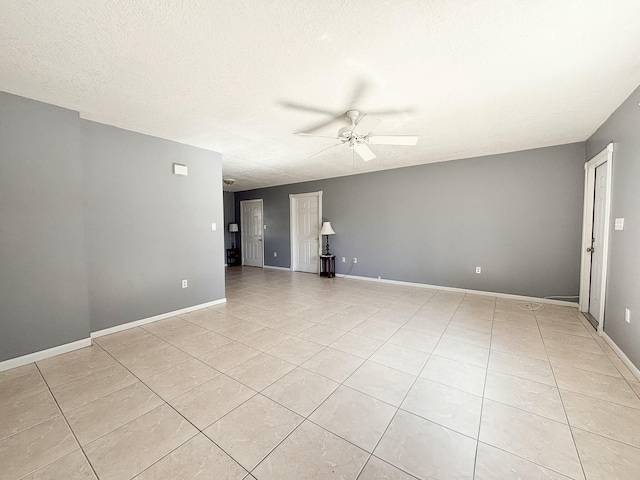 tiled empty room with ceiling fan and a textured ceiling