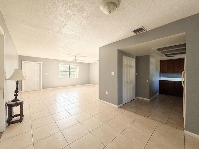 empty room featuring ceiling fan, light tile patterned floors, and a textured ceiling