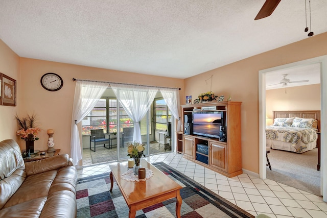 living room with a textured ceiling, ceiling fan, and light tile patterned floors