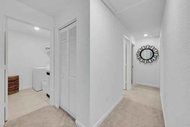 corridor with light colored carpet and washer / clothes dryer