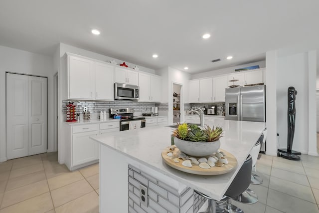 kitchen featuring white cabinets, an island with sink, stainless steel appliances, and sink