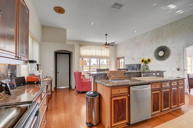 kitchen featuring sink, ceiling fan, an island with sink, appliances with stainless steel finishes, and light hardwood / wood-style floors