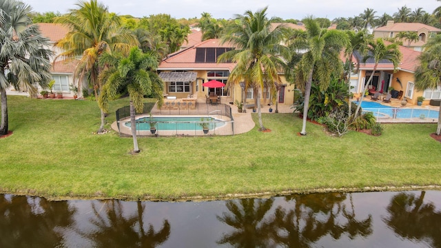 rear view of house with a lawn, a water view, and a patio