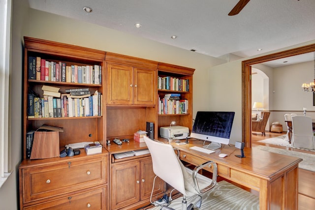 office space featuring ceiling fan with notable chandelier