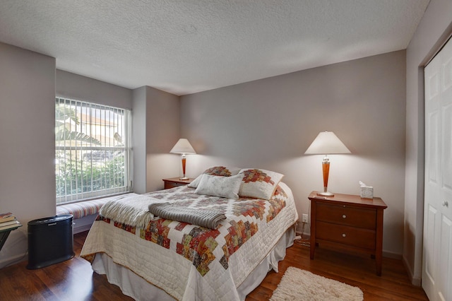 bedroom with dark hardwood / wood-style floors, a textured ceiling, and a closet