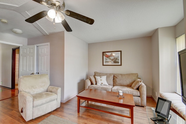 living room featuring ceiling fan, a textured ceiling, and light hardwood / wood-style flooring