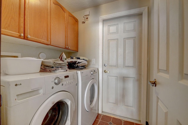 laundry room with washer and dryer, dark tile patterned floors, cabinets, and a textured ceiling