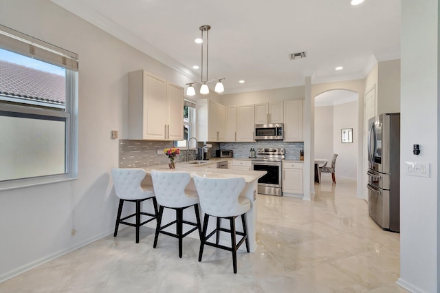 kitchen featuring kitchen peninsula, stainless steel appliances, sink, white cabinets, and hanging light fixtures