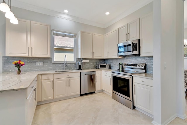 kitchen featuring sink, tasteful backsplash, light stone counters, pendant lighting, and appliances with stainless steel finishes