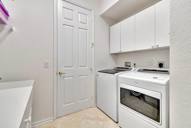 laundry area featuring washer and clothes dryer, light tile patterned flooring, and cabinets