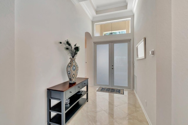 entrance foyer with ornamental molding, a towering ceiling, and french doors