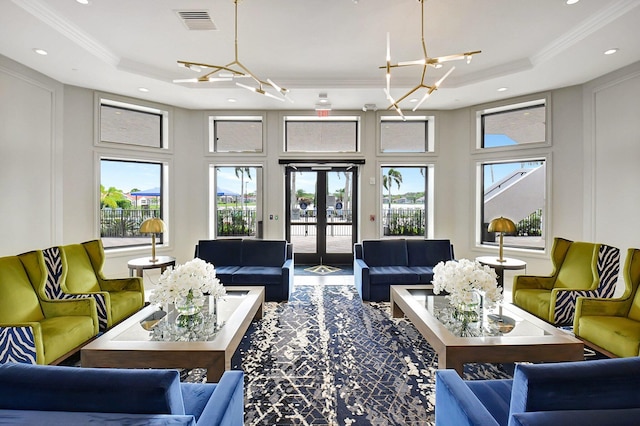 living room featuring a chandelier, a raised ceiling, and a healthy amount of sunlight