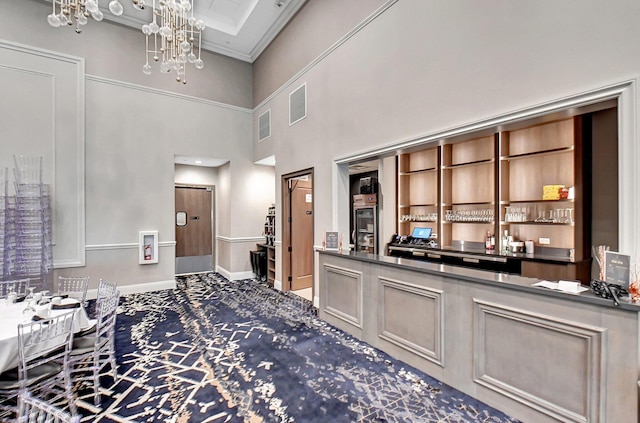 bar featuring carpet flooring, a towering ceiling, an inviting chandelier, and crown molding