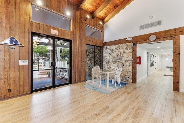 unfurnished dining area featuring beam ceiling, light hardwood / wood-style flooring, high vaulted ceiling, and wood ceiling