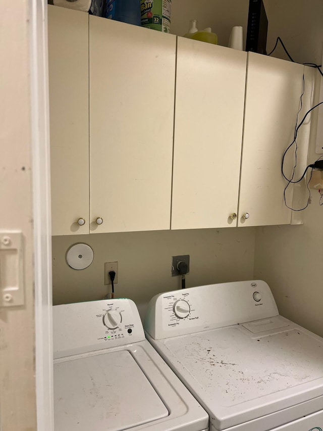 clothes washing area featuring cabinets and washing machine and clothes dryer