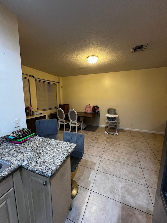 kitchen featuring light stone counters, a textured ceiling, and light tile patterned flooring