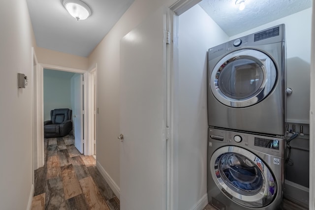 clothes washing area with stacked washer and dryer, dark hardwood / wood-style flooring, and a textured ceiling