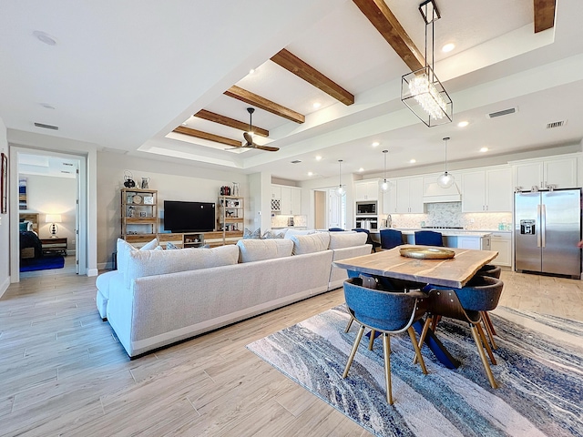 living room with a tray ceiling, ceiling fan, and beamed ceiling