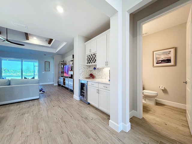 kitchen with white cabinetry, light wood-type flooring, decorative backsplash, and wine cooler