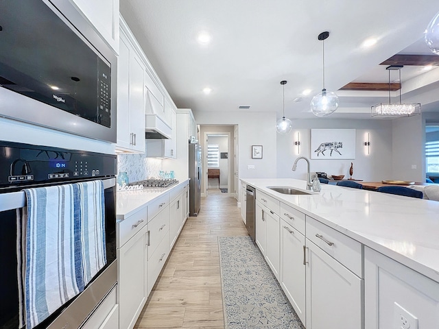 kitchen featuring pendant lighting, sink, white cabinets, and appliances with stainless steel finishes