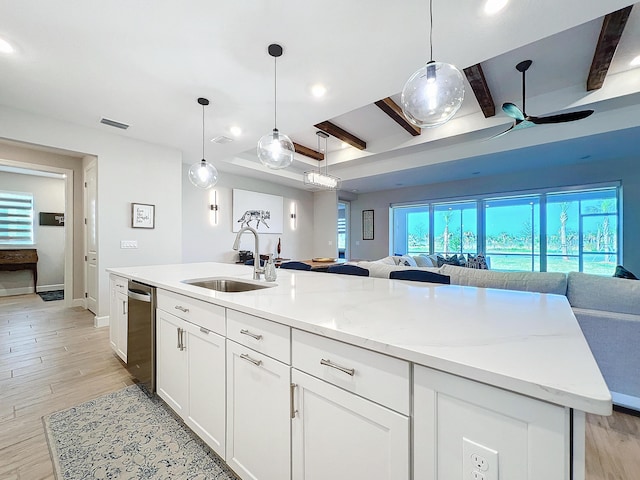 kitchen featuring sink, white cabinets, a center island with sink, decorative light fixtures, and beamed ceiling