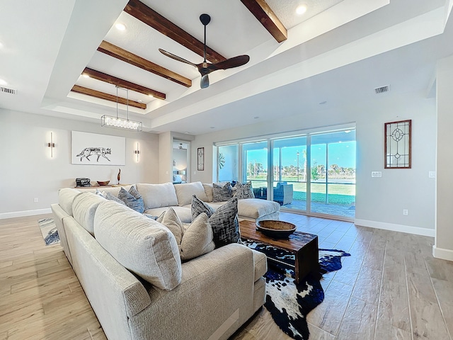 living room featuring ceiling fan, light wood-type flooring, beam ceiling, and a tray ceiling