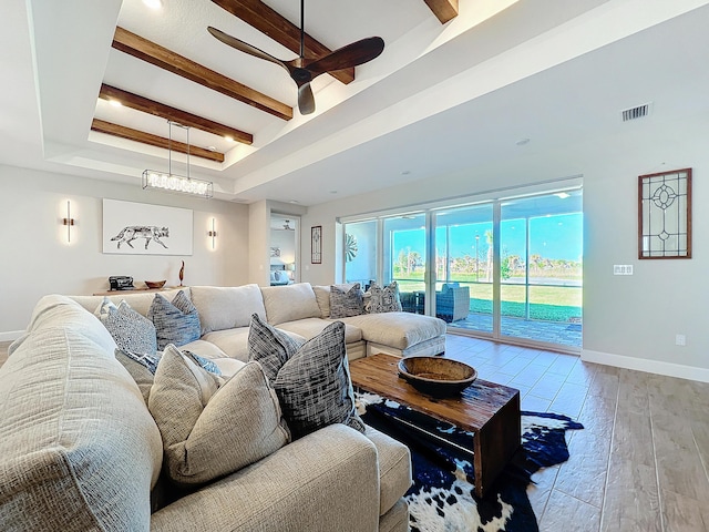 living room featuring ceiling fan, beam ceiling, a raised ceiling, and light hardwood / wood-style floors