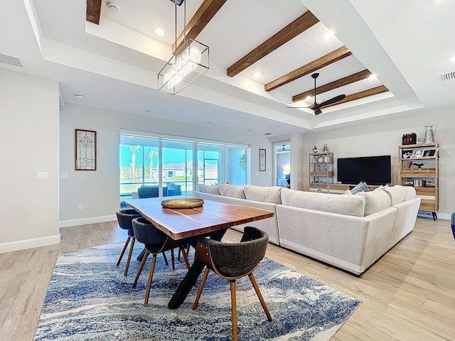 dining space with light hardwood / wood-style floors, a raised ceiling, and ceiling fan