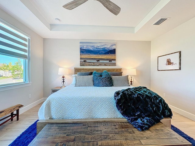 bedroom with a raised ceiling, hardwood / wood-style flooring, and ceiling fan