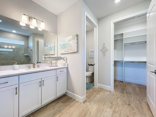 bathroom featuring vanity, toilet, and tiled shower