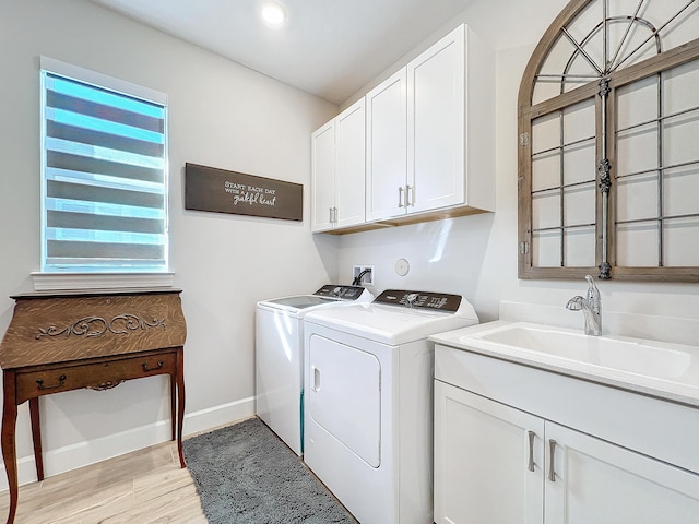 laundry area with cabinets, sink, independent washer and dryer, and light wood-type flooring