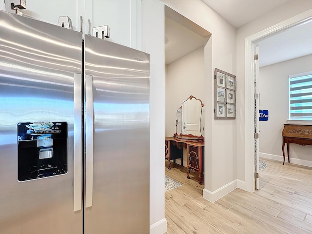 kitchen with stainless steel refrigerator with ice dispenser, white cabinets, and light hardwood / wood-style flooring