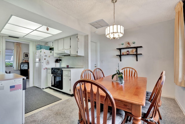 carpeted dining area featuring a chandelier and a textured ceiling