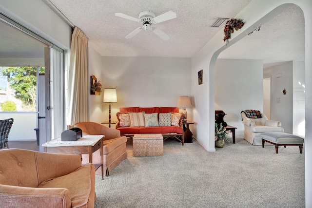 living room with ceiling fan, carpet floors, and a textured ceiling