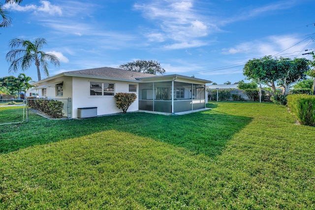 back of property with a sunroom and a yard