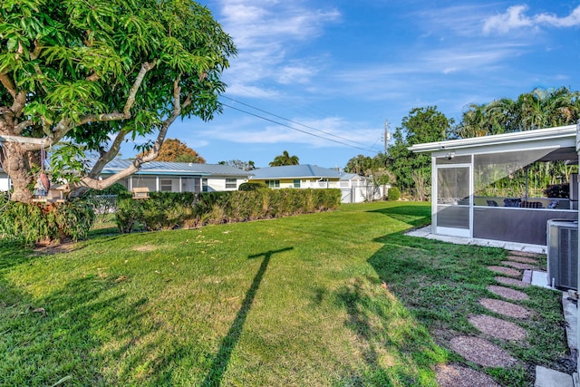 view of yard with a sunroom and central AC unit