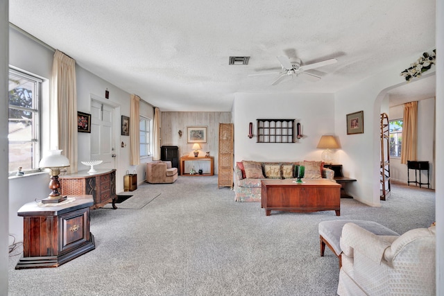 living room with light carpet, a textured ceiling, and ceiling fan