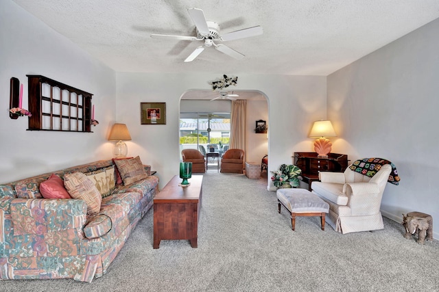 living room with carpet flooring, ceiling fan, and a textured ceiling