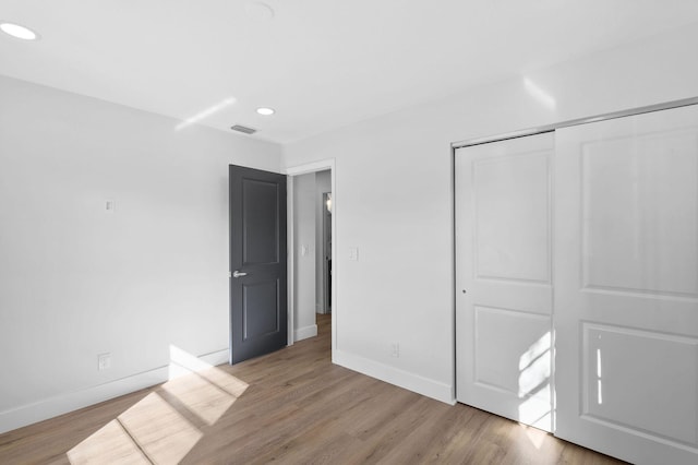 unfurnished bedroom with a closet and light wood-type flooring