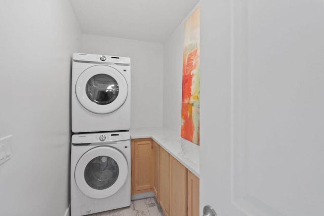 clothes washing area with stacked washing maching and dryer and cabinets