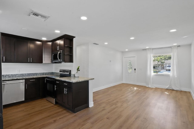 kitchen with light wood-type flooring, stainless steel appliances, dark brown cabinets, and light stone counters