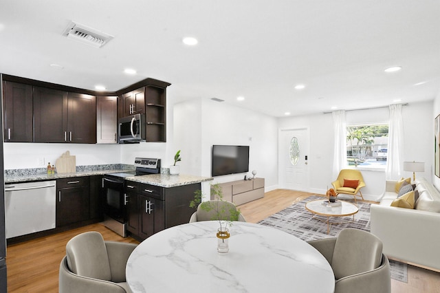 kitchen featuring light stone counters, light hardwood / wood-style flooring, dark brown cabinetry, and stainless steel appliances