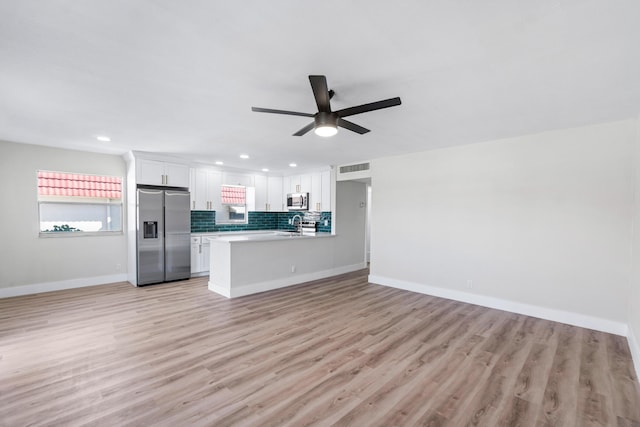 kitchen with stainless steel appliances, white cabinets, ceiling fan, light hardwood / wood-style floors, and kitchen peninsula